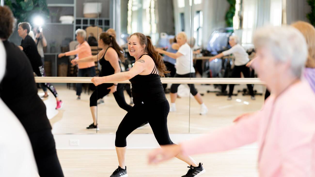 A group of women taking an exercise class with an instructor at the movement studio.