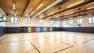 An indoor sports court with court markings for basketball and pickleball.