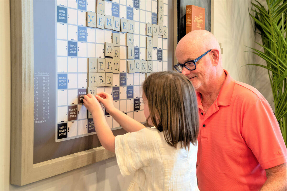 Grandfather playing Scrabble with his granddaughter in the Indigo Game Room.