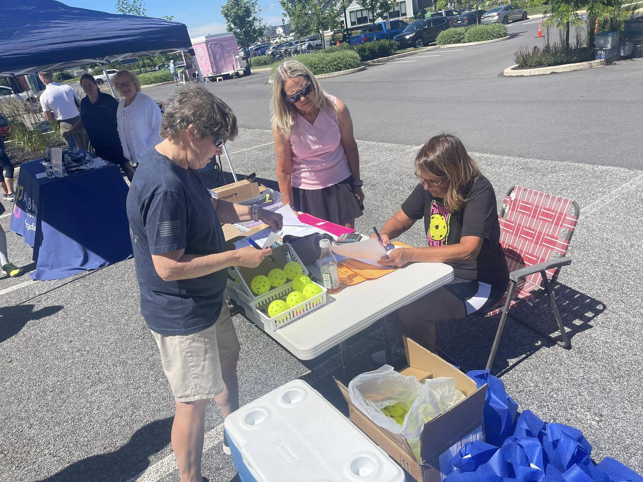 Roots for Boots pickleball tournament volunteers checking in competitors outdoors