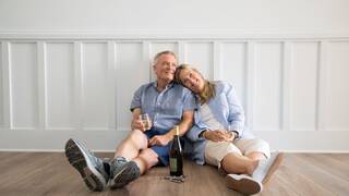 Retired couple sharing wine in the new home they have purchased together