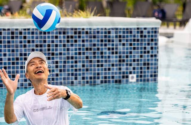 Retirement age man playing volleyball in the pool