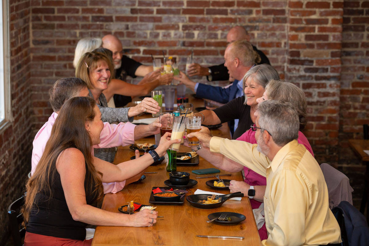A group of Amblebrook residents toasting with drinks at a restaurant, celebrating together.